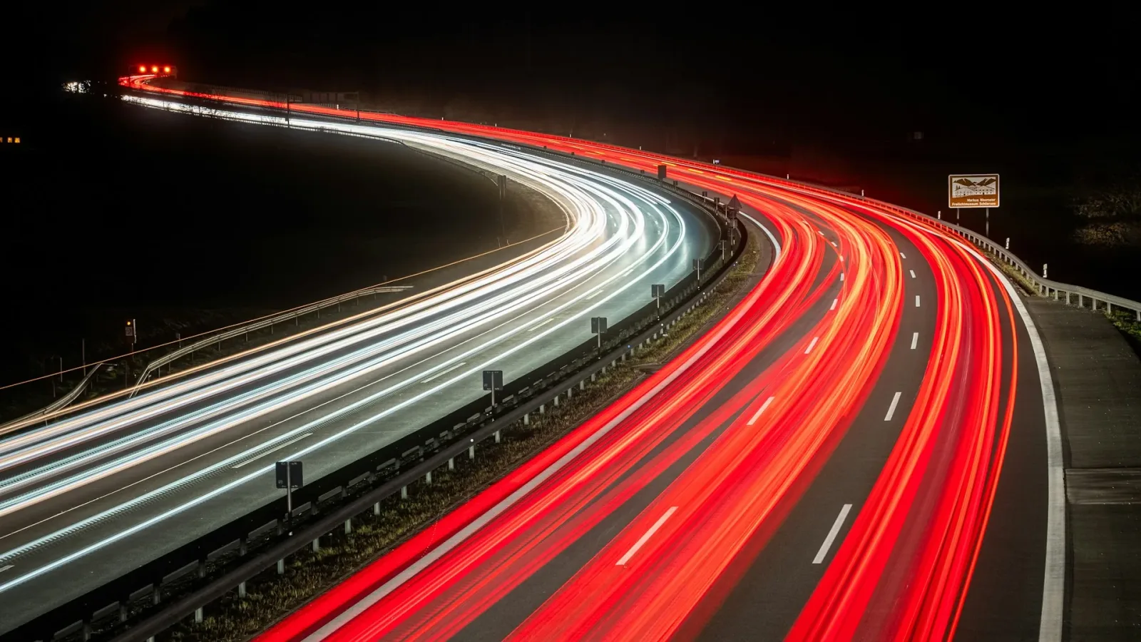 Nächtliche Autobahn mit Lichtspuren eilender Fahrzeuge