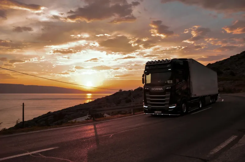 Sattelzug der RNS Logistik auf einer K&uuml;stenstra&szlig;e im Sonnenuntergang